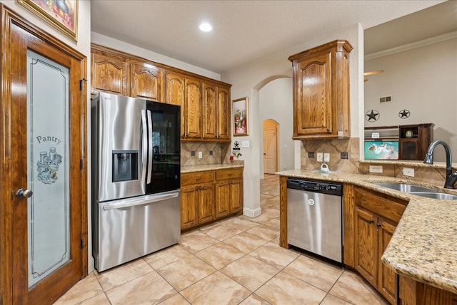 kitchen with appliances with stainless steel finishes, light tile patterned flooring, decorative backsplash, and sink