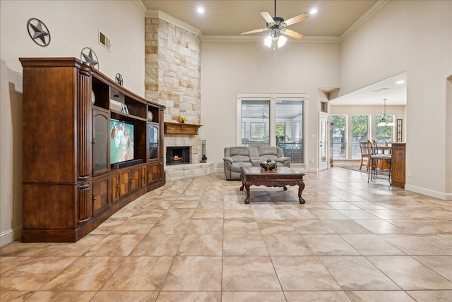 living room featuring a fireplace, ceiling fan, a high ceiling, crown molding, and light tile patterned floors