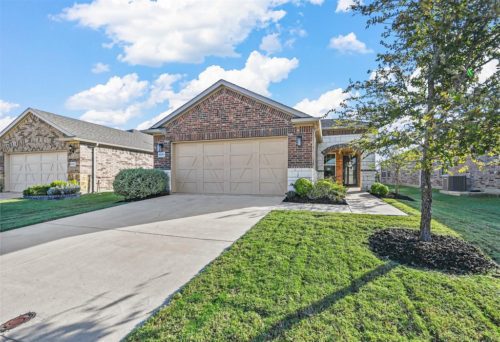 view of front of house featuring a front lawn, central AC unit, and a garage