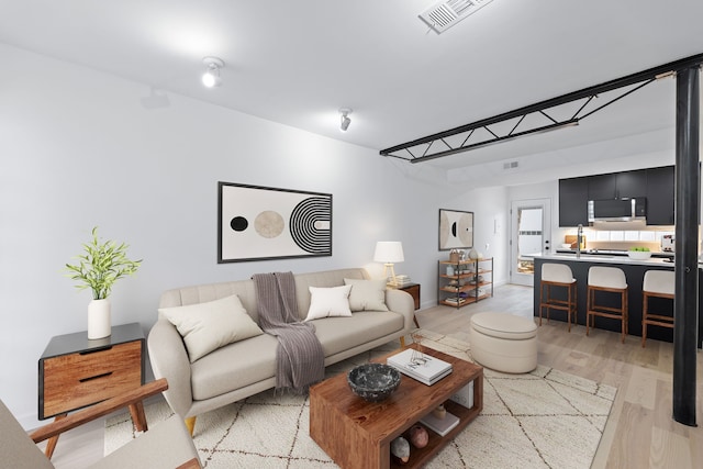 living area featuring light wood-style floors, baseboards, and visible vents