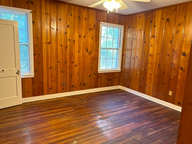 spare room with dark hardwood / wood-style flooring, wooden walls, ceiling fan, and crown molding