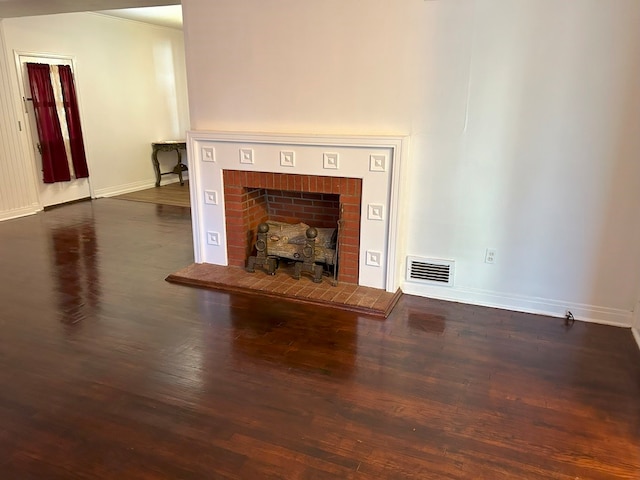 unfurnished living room with dark wood-type flooring and a fireplace