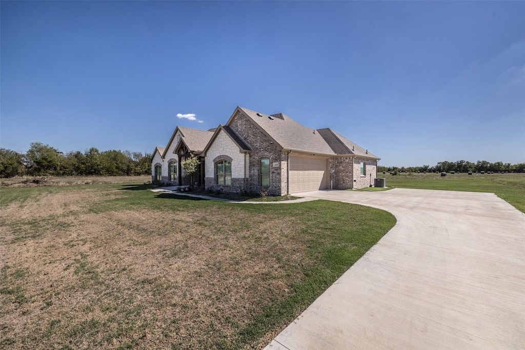 view of front of property featuring central AC, a garage, and a front lawn