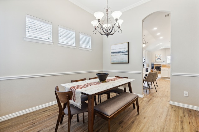 dining room with crown molding, a notable chandelier, lofted ceiling, and light wood-type flooring