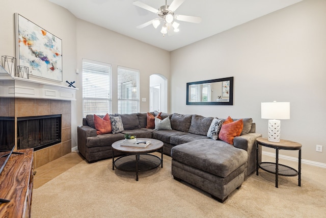 carpeted living room with ceiling fan and a tile fireplace