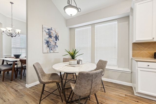 dining room with vaulted ceiling, light hardwood / wood-style flooring, and an inviting chandelier