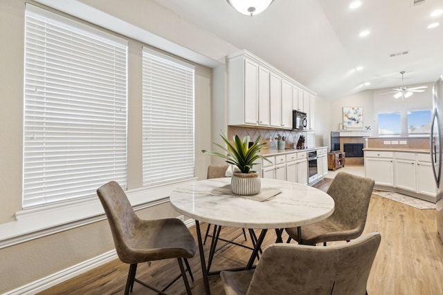 dining area featuring vaulted ceiling, light wood-type flooring, and ceiling fan