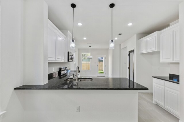 kitchen with kitchen peninsula, sink, white cabinetry, and stainless steel appliances