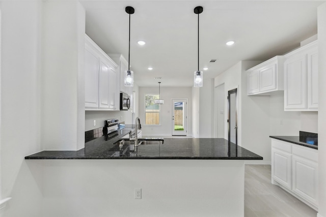 kitchen with pendant lighting, appliances with stainless steel finishes, white cabinetry, a sink, and a peninsula