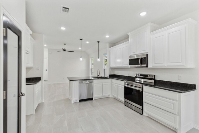 kitchen featuring kitchen peninsula, stainless steel appliances, sink, white cabinetry, and hanging light fixtures