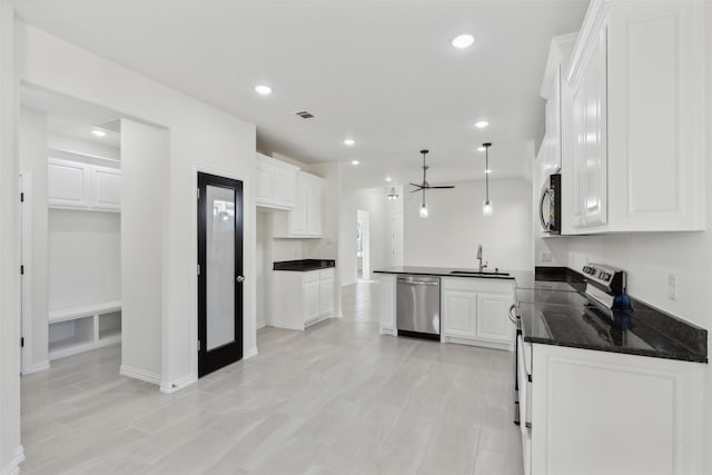 kitchen with stainless steel appliances, dark countertops, white cabinets, and a sink