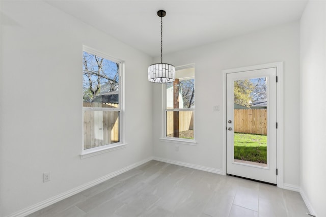 unfurnished dining area with baseboards and an inviting chandelier