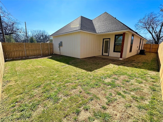 rear view of property with a shingled roof, a fenced backyard, a lawn, and central air condition unit