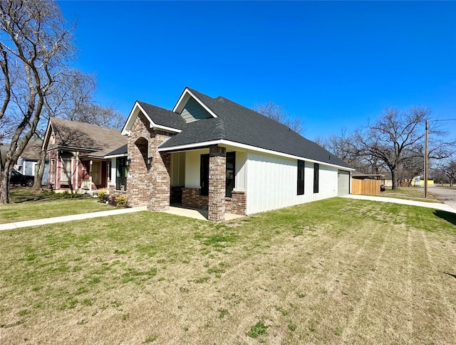 view of side of home featuring driveway, a shingled roof, a lawn, an attached garage, and brick siding