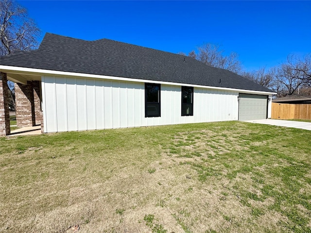 back of house featuring a garage, a shingled roof, and a yard