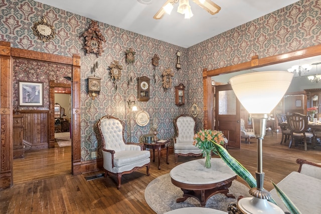 living area featuring hardwood / wood-style floors and ceiling fan with notable chandelier