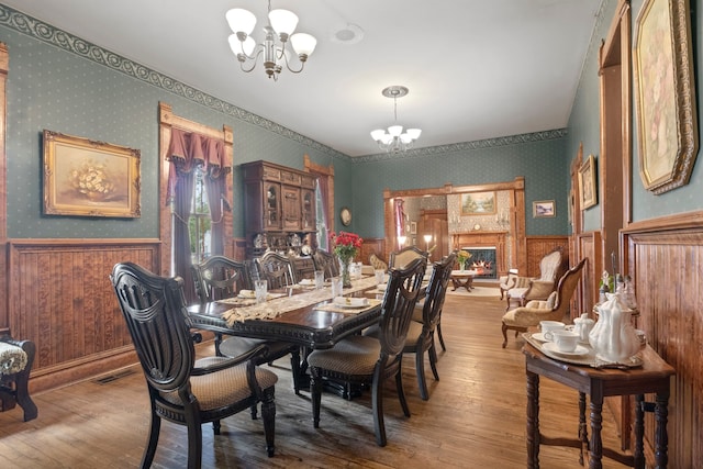 dining room featuring hardwood / wood-style flooring, an inviting chandelier, and wood walls