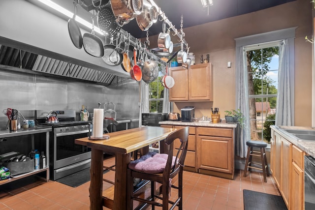 kitchen with black dishwasher, light brown cabinetry, light tile patterned floors, and stainless steel stove