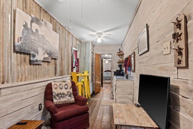 interior space featuring wooden walls, sink, and light wood-type flooring