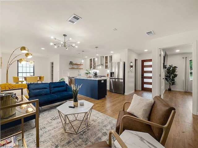 living room with light wood-type flooring, sink, and a chandelier