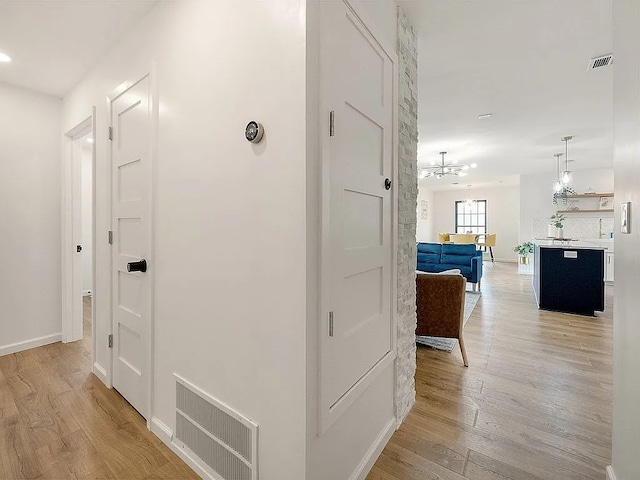 corridor featuring light hardwood / wood-style floors and a notable chandelier