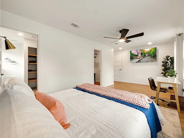 bedroom featuring a walk in closet, ceiling fan, a closet, and hardwood / wood-style flooring