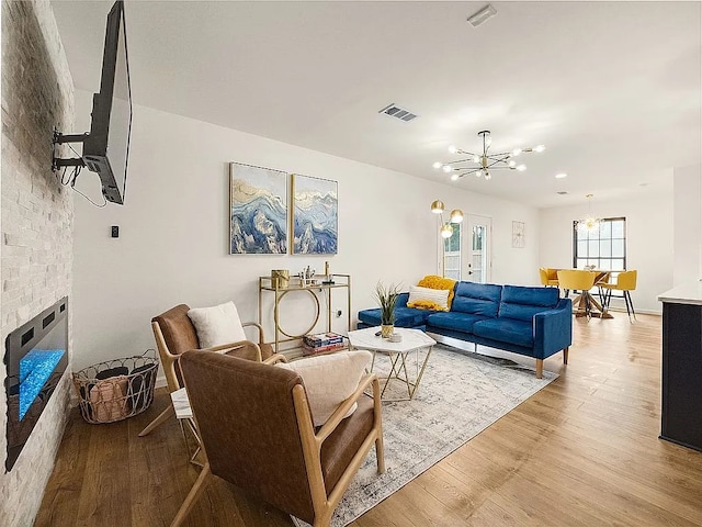 living room featuring a fireplace, light hardwood / wood-style flooring, and a notable chandelier