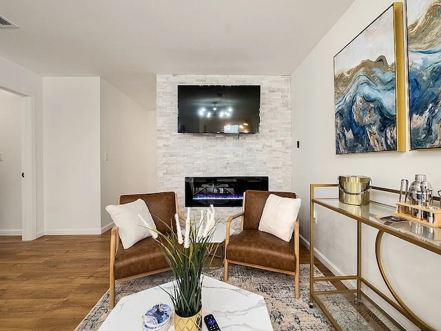 living area featuring hardwood / wood-style floors and a stone fireplace