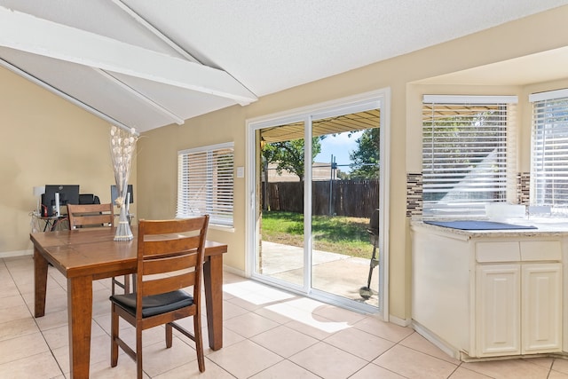 tiled dining area with a textured ceiling and vaulted ceiling