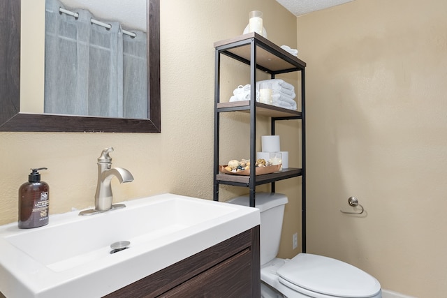 bathroom featuring toilet, a textured ceiling, and vanity