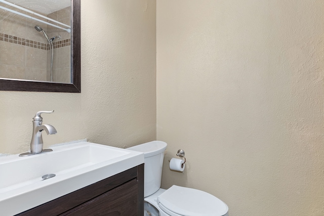 bathroom with vanity, toilet, and tiled shower