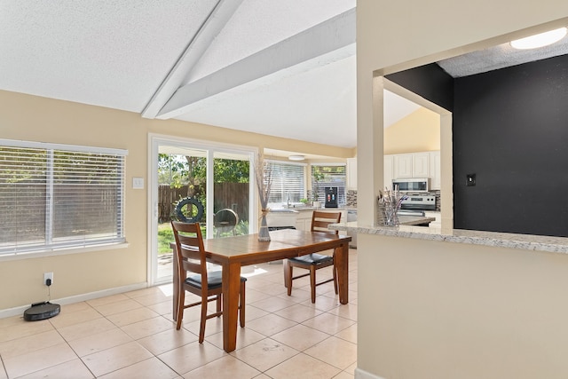 dining space featuring light tile patterned floors, a textured ceiling, and vaulted ceiling