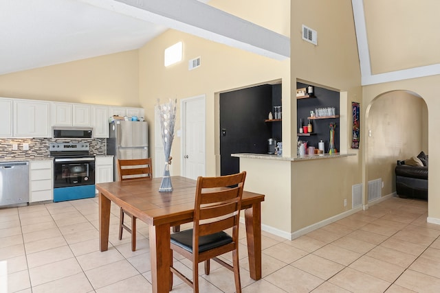 dining room with high vaulted ceiling and light tile patterned floors