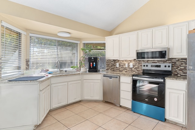 kitchen featuring appliances with stainless steel finishes, sink, vaulted ceiling, white cabinets, and light tile patterned floors