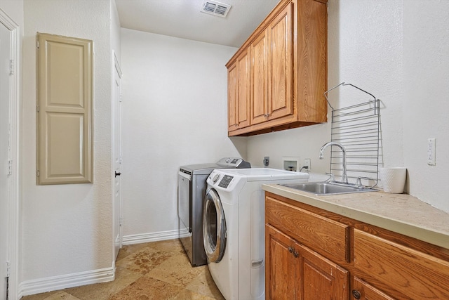 clothes washing area with cabinets, sink, and washing machine and dryer