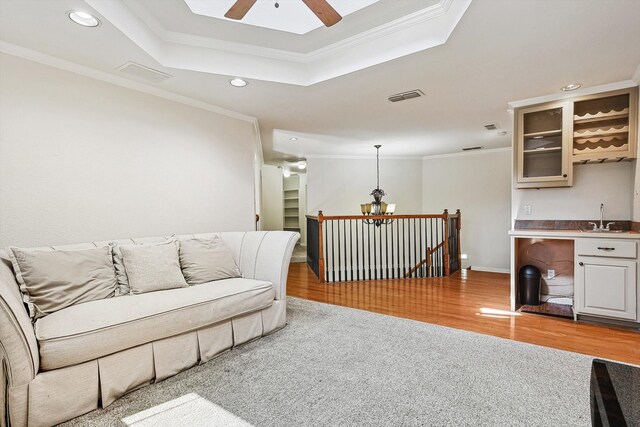 living room featuring light hardwood / wood-style floors, a raised ceiling, ceiling fan, and crown molding