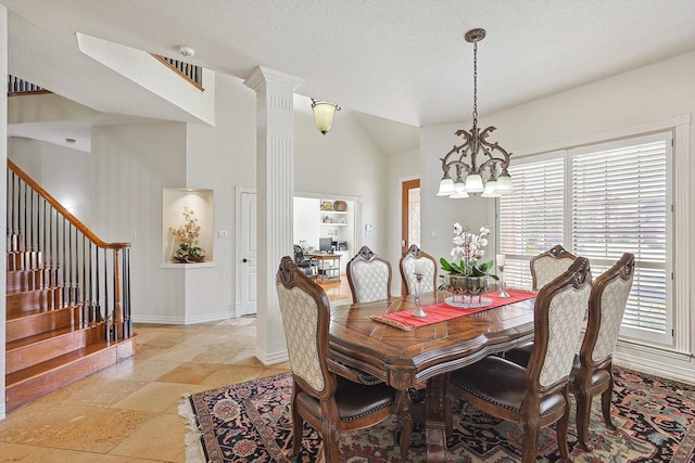 dining space with decorative columns, a textured ceiling, high vaulted ceiling, and a chandelier