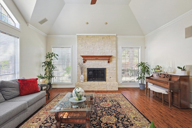 living room with hardwood / wood-style floors, high vaulted ceiling, a stone fireplace, and crown molding