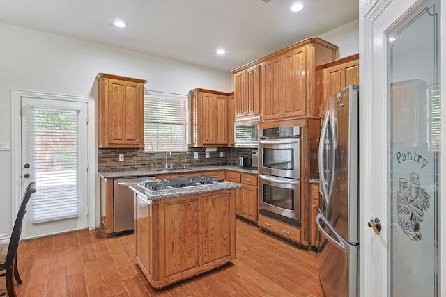 kitchen featuring sink, a center island, stainless steel appliances, and light hardwood / wood-style flooring