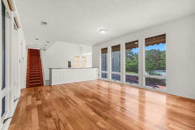 unfurnished living room with light hardwood / wood-style floors, a towering ceiling, and a fireplace