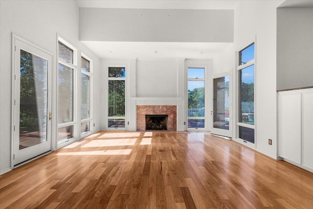 unfurnished living room with beam ceiling, high vaulted ceiling, light wood-type flooring, and a tile fireplace