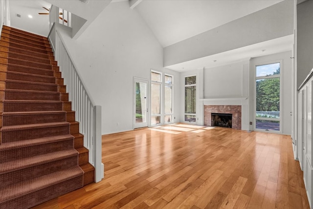 unfurnished living room with a tile fireplace, light wood-type flooring, and a healthy amount of sunlight