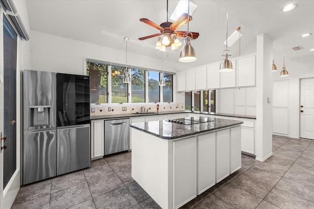 kitchen featuring backsplash, a center island, stainless steel appliances, pendant lighting, and lofted ceiling with skylight