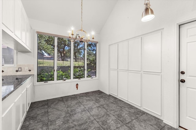 kitchen with stainless steel double oven, dark stone counters, decorative light fixtures, white cabinets, and high vaulted ceiling