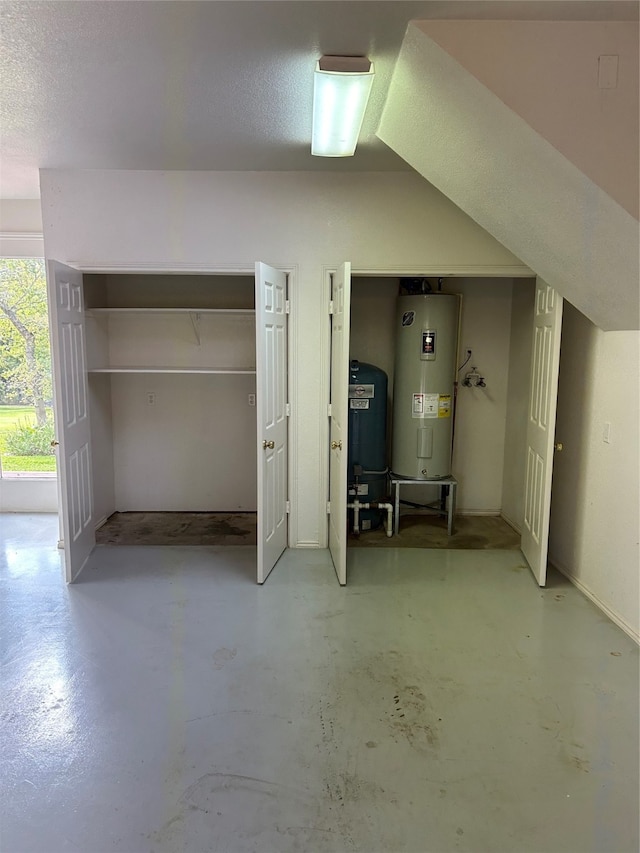 basement with water heater and a textured ceiling