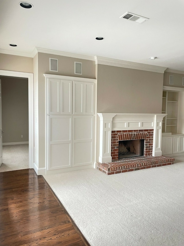 unfurnished living room with dark wood-type flooring, a brick fireplace, and crown molding