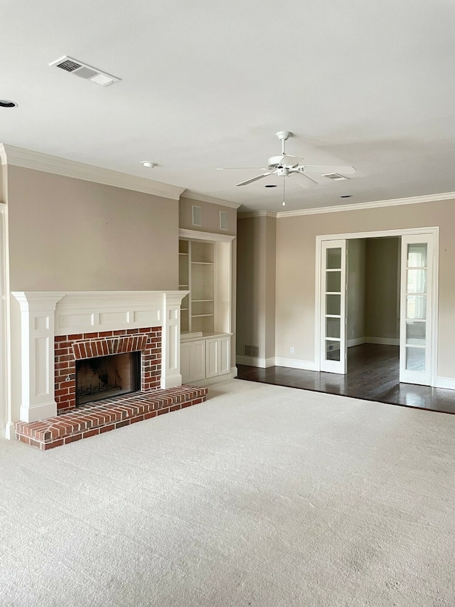 unfurnished living room featuring a fireplace, ornamental molding, carpet, and ceiling fan