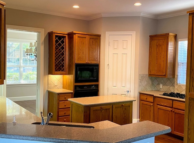 kitchen with a kitchen island, decorative backsplash, crown molding, and black appliances