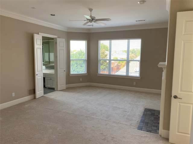 unfurnished bedroom with ornamental molding, ensuite bath, light colored carpet, and ceiling fan