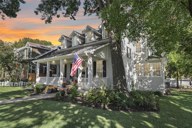 new england style home with a porch and a lawn